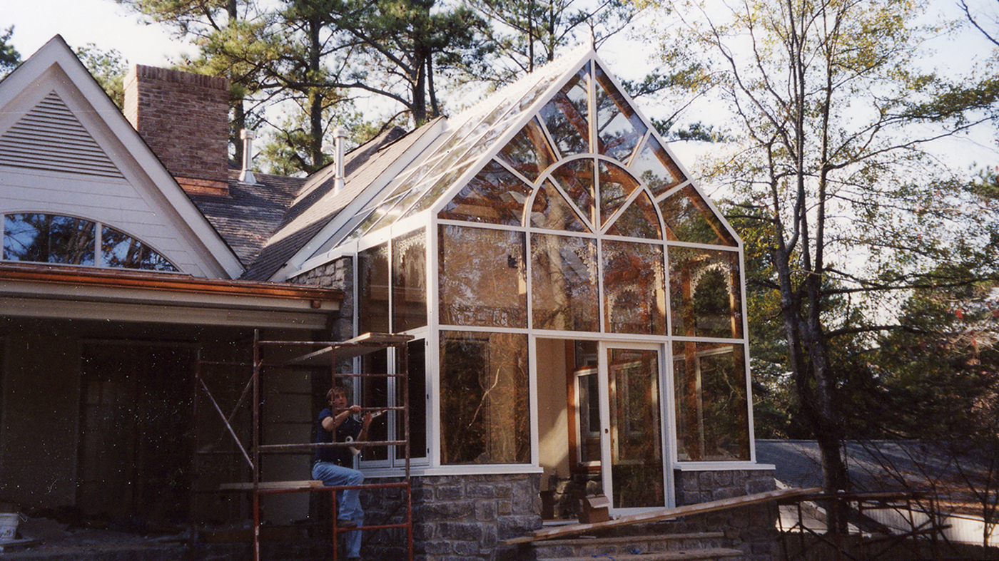 Straight eave double pitch conservatory with a finial, ridge cresting, gable pediment, and decorative corners.