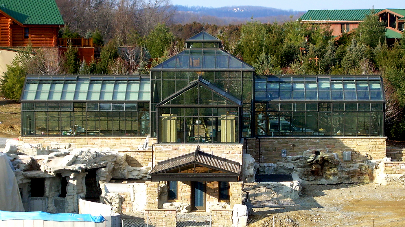 Straight eave double pitch structures attached to a central hip end greenhouse with a canopy entryway and a pyramidal cupola