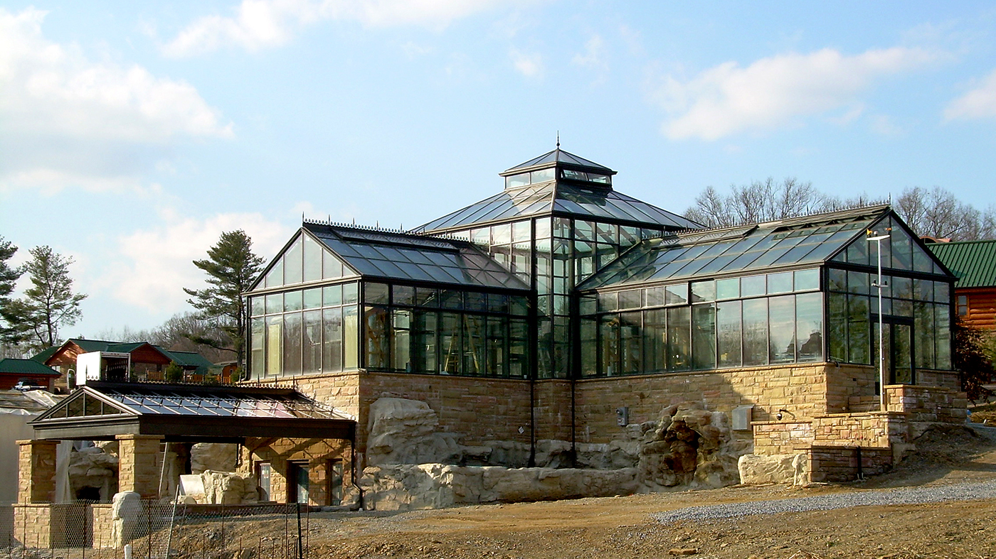 Straight eave double pitch structures attached to a central hip end greenhouse with a canopy entryway and a pyramidal cupola