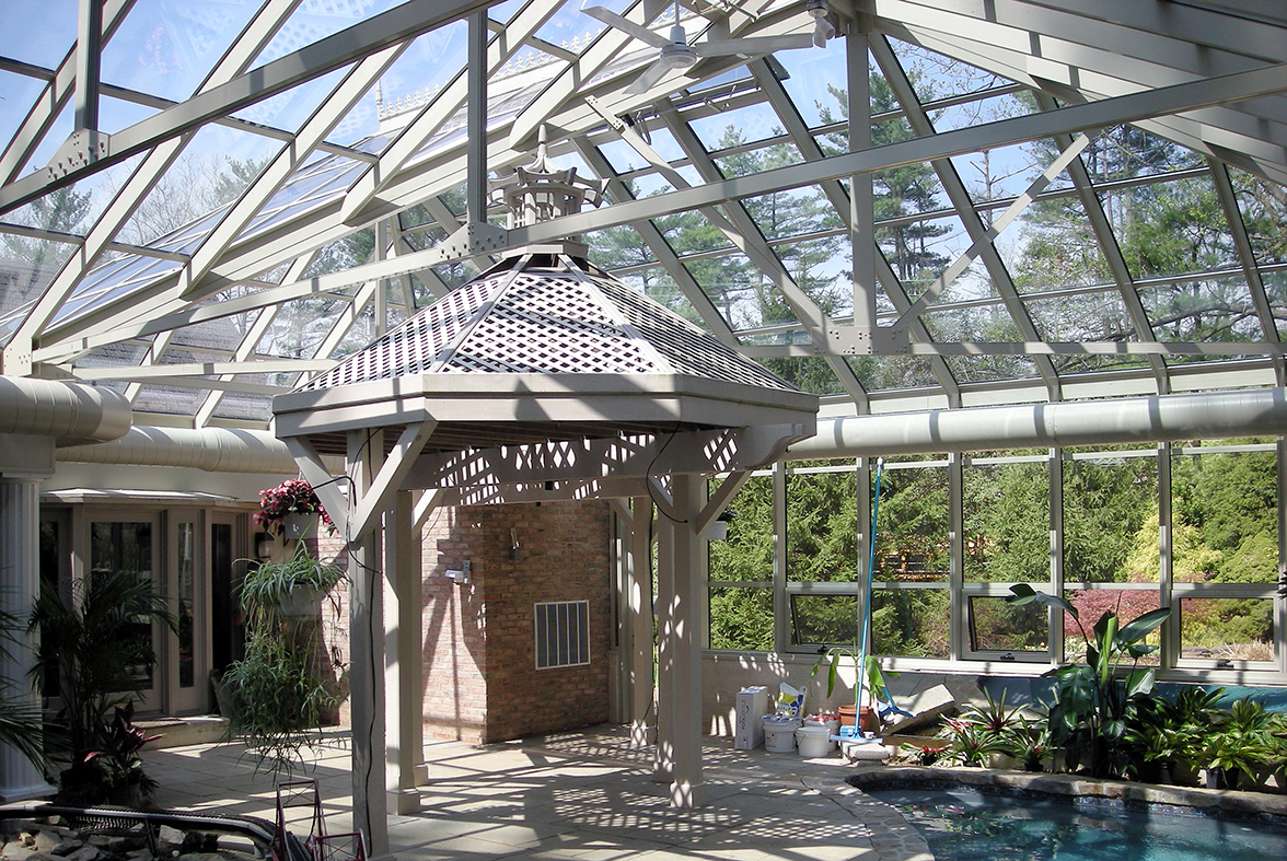 Straight-eave double pitch pool enclosure with two hip ends, one irregular hip corner, two full sidewalls, and one partial end wall. Unit includes awning windows, ridge cresting, finial and terrace door.