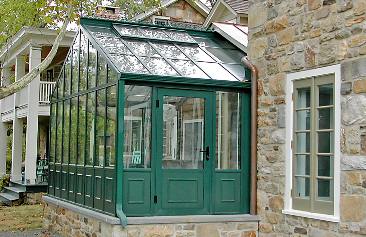 Straight eave double pitch, conservatory greenhouse with decorative base panels, ridge cresting, operable ridge vents, and decorative corners.