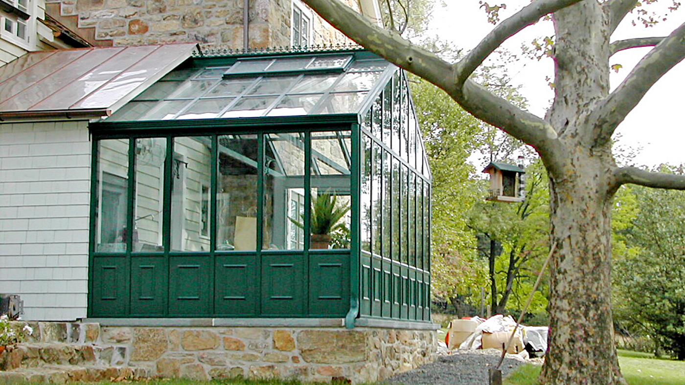 Straight eave double pitch, conservatory greenhouse with decorative base panels, ridge cresting, operable ridge vents, and decorative corners.