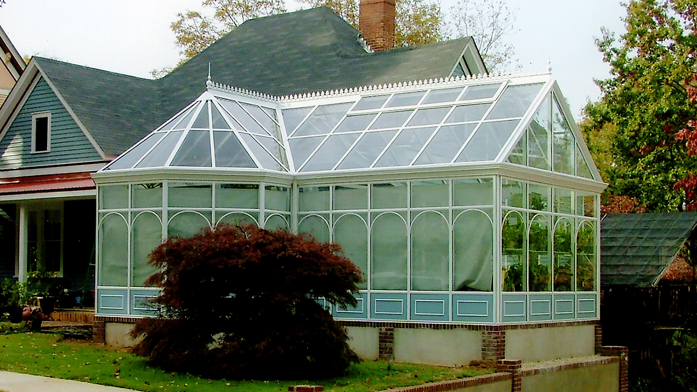 Straight eave, double pitch orchid greenhouse with bull nose, partial lean-to roof section, ridge cresting, finials, and grids.