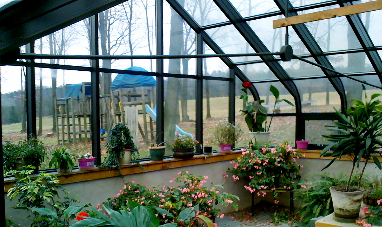 Curved eave double pitch greenhouse with two gable ends and a curved eave double pitch dormer with one gable end. Features operable ridge vent, decorative alumnim ridge cresting, terrace door and interior ring and collar.
