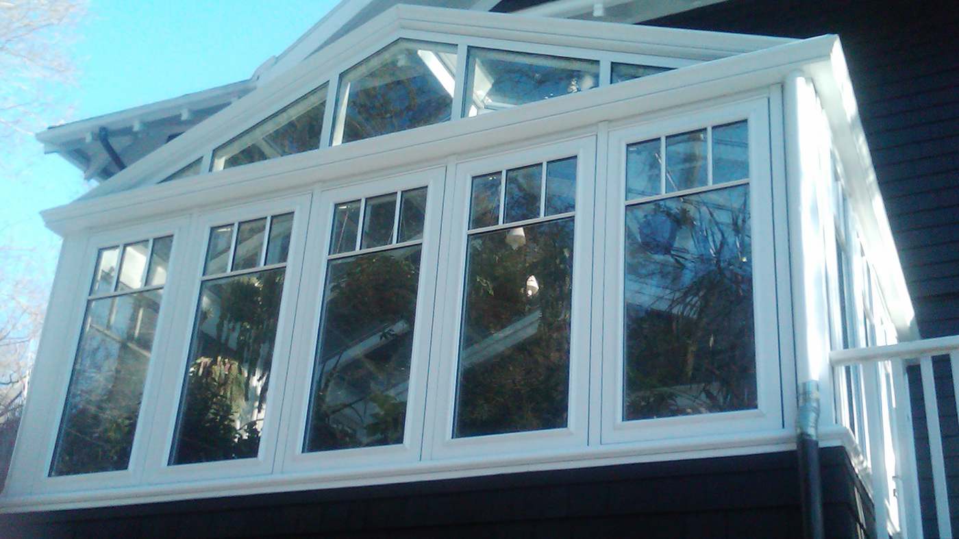 Straight eave double pitch conservatory with one gable end. Structure includes SDL grids designed to mimic a transom, gutter, downspout, crown molding on gable and interior ogee capping.
