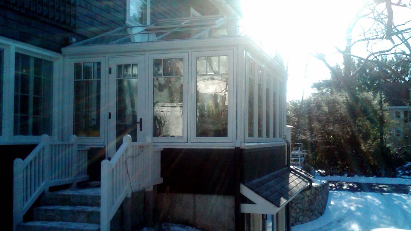 Straight eave double pitch conservatory with one gable end. Structure includes SDL grids designed to mimic a transom, gutter, downspout, crown molding on gable and interior ogee capping.