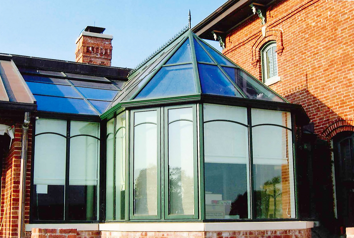 Straight eave lean to sunroom with irregular conservatory nose dormer. Decorative options include: ridge cresting, finial, and SDL grids in a radius arched pattern.