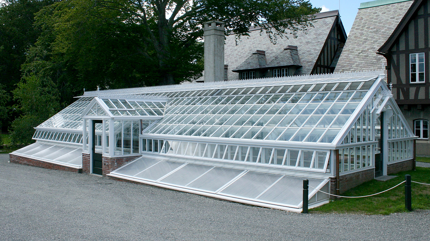 Straight eave, double pitch greenhouse with dormer, ridge cresting, and finial. Restoration System with cold frame.