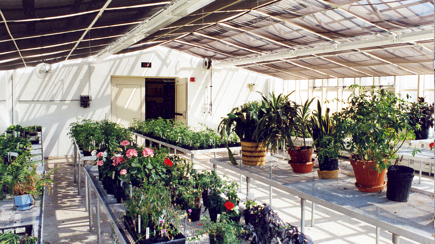 Straight eave double pitch greenhouse with operable ridge and eave vents and interior operable shades.