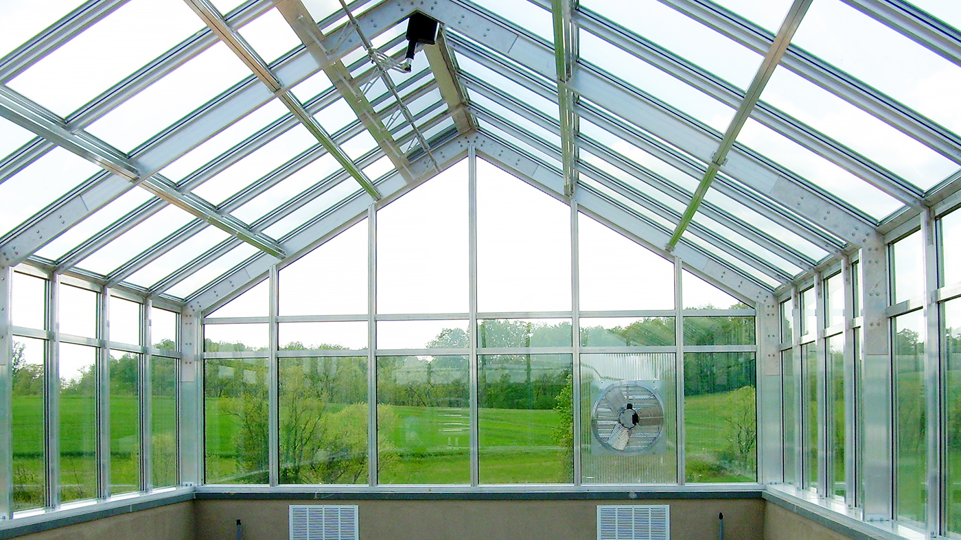 Straight eave double pitch I-Beam greenhouse with two gable ends; includes French door, operable ridge vents, evaporation coolers, shutter fan, and greenhouse benches.