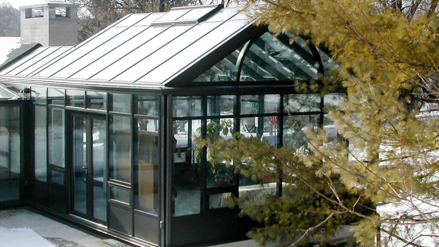 Custom Sunroom configuration: (1) straight eave double pitch and (1) straight eave lean-to Sunroom connected by an enclosed walkway. Decorative elements include: radius arch in gable end, solid base panel, gutter, and downspouts.