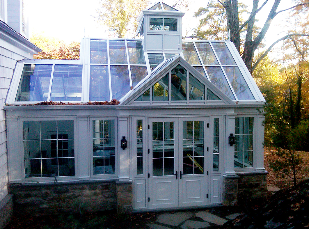 Straight eave double pitch greenhouse with one gable end two attached double pitch dormers and one pyramid cupola.