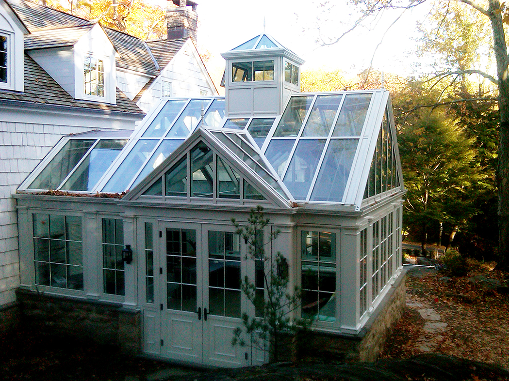 Straight eave double pitch greenhouse with one gable end two attached double pitch dormers and one pyramid cupola.