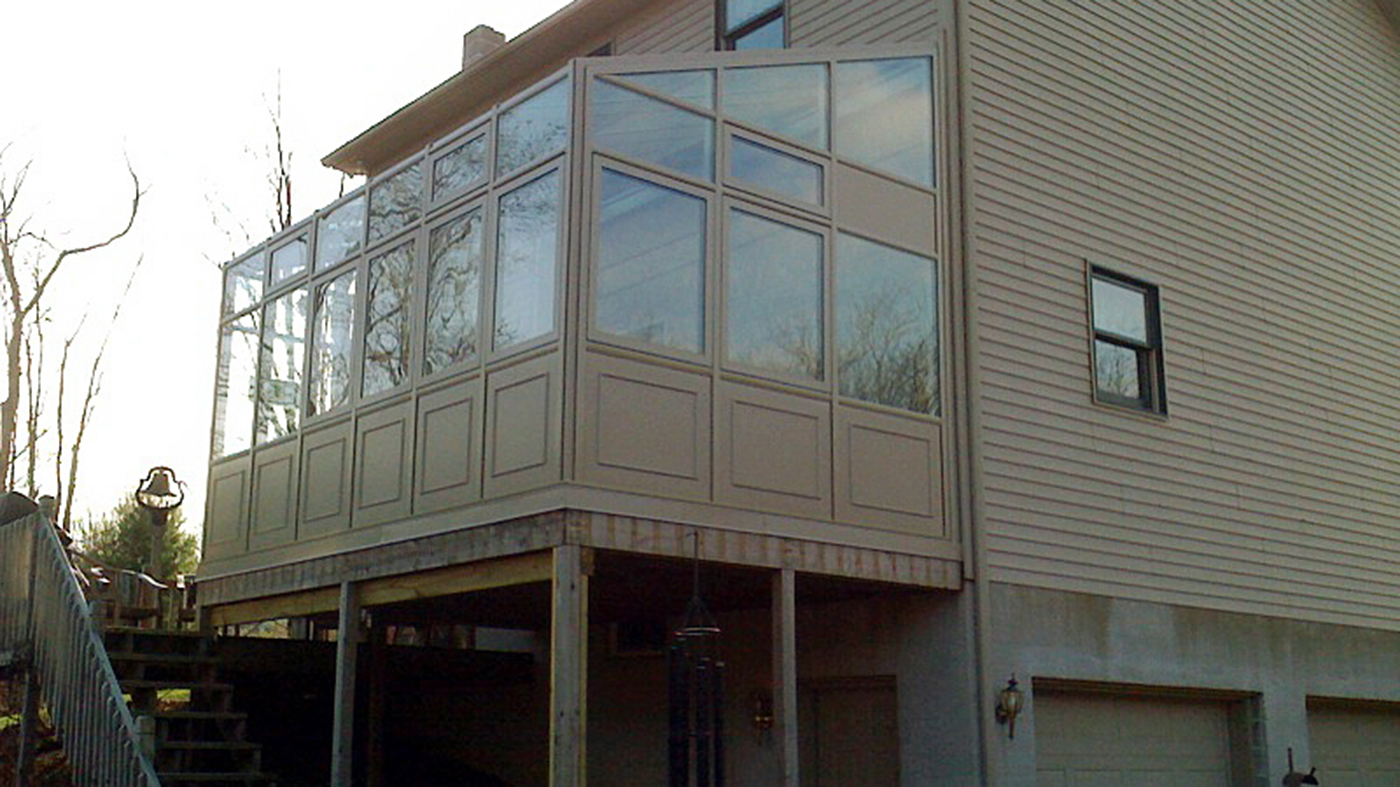 Straight eave lean to sunroom with two gable ends, a sliding door system, operable windows and raised base panels.