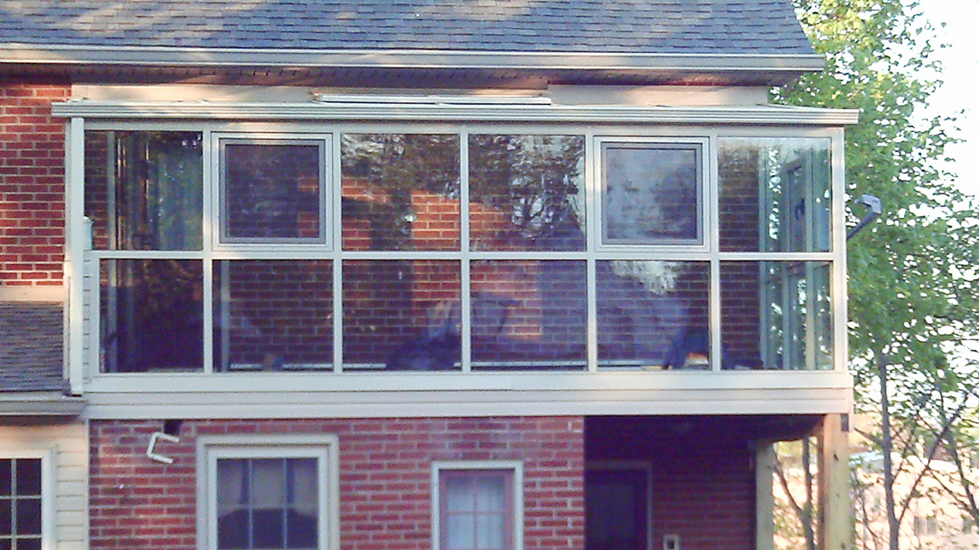 Straight eave lean-to sunroom with two gable ends, located on a second story application, with tilt turn windows and a ridge vent.