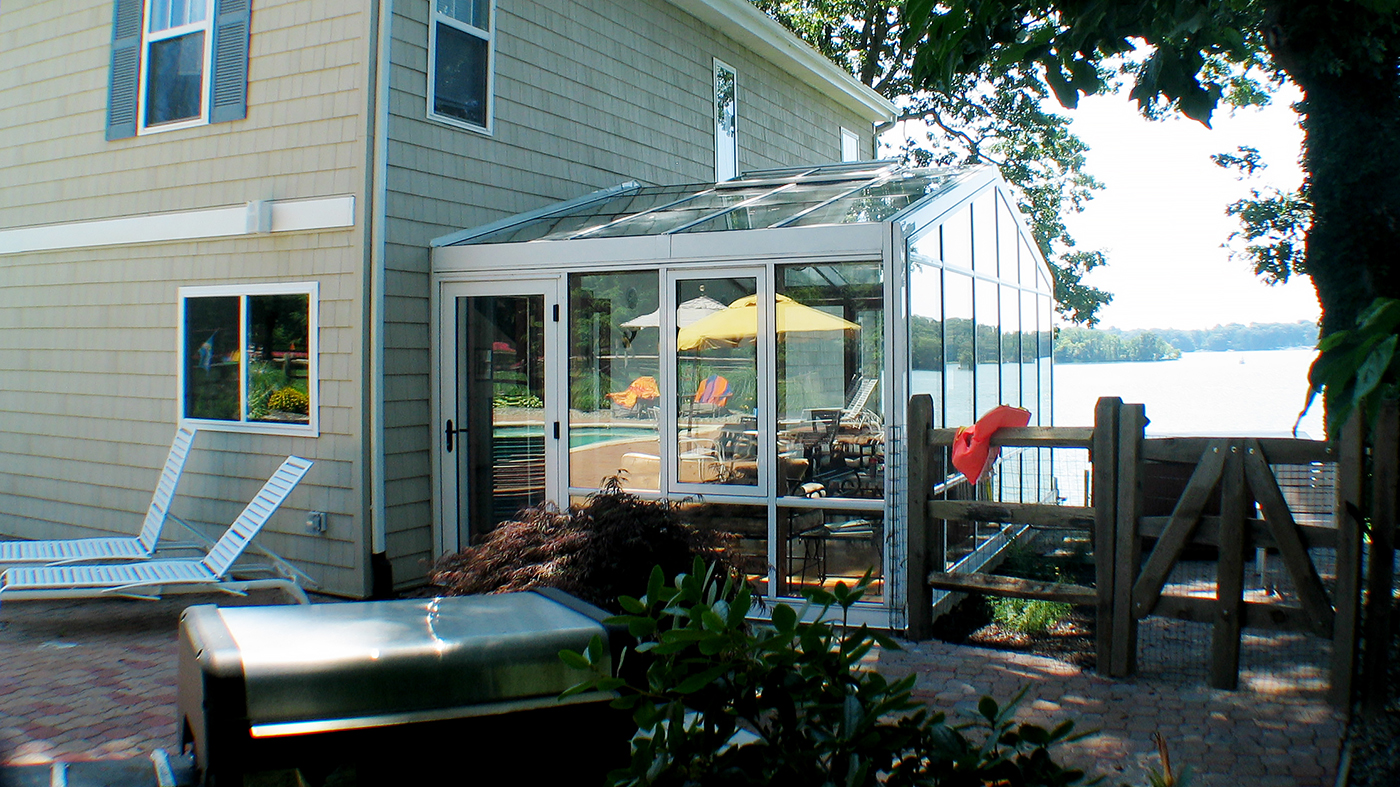Straight eave double pitch sunroom with one gable end, aluminum exterior with a mahogany wood interior, ridge vents, windows and terrace door.