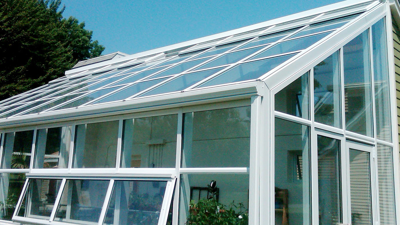 Irregular straight eave lean to greenhouse with operable eave sashes and ridge vents, terrace door, gutter and downspout.