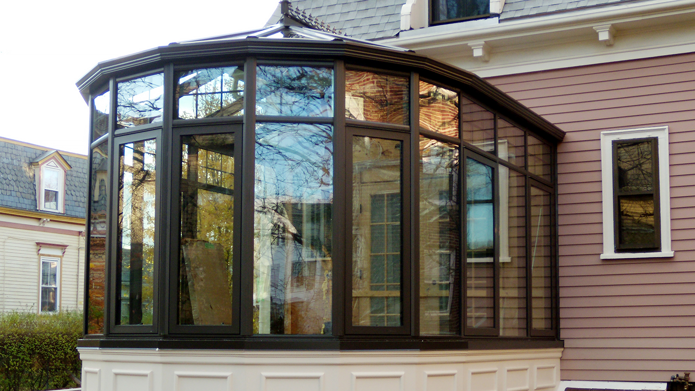 Transoms create a geometric pattern around the top of the 8-panel nose of this conservatory. Other decorative elements include ridge vents, ridge cresting, finials, and interior muntins.