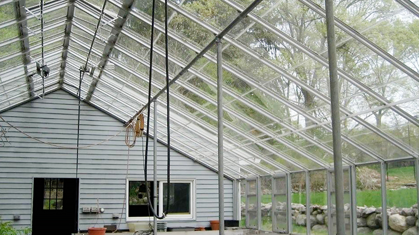 Existing greenhouse with retrofits by Solar Innovations. Additions include an operable, roof mounted shade system, humidifiers, ridge vent replacement, and fixed mesh top benches.P