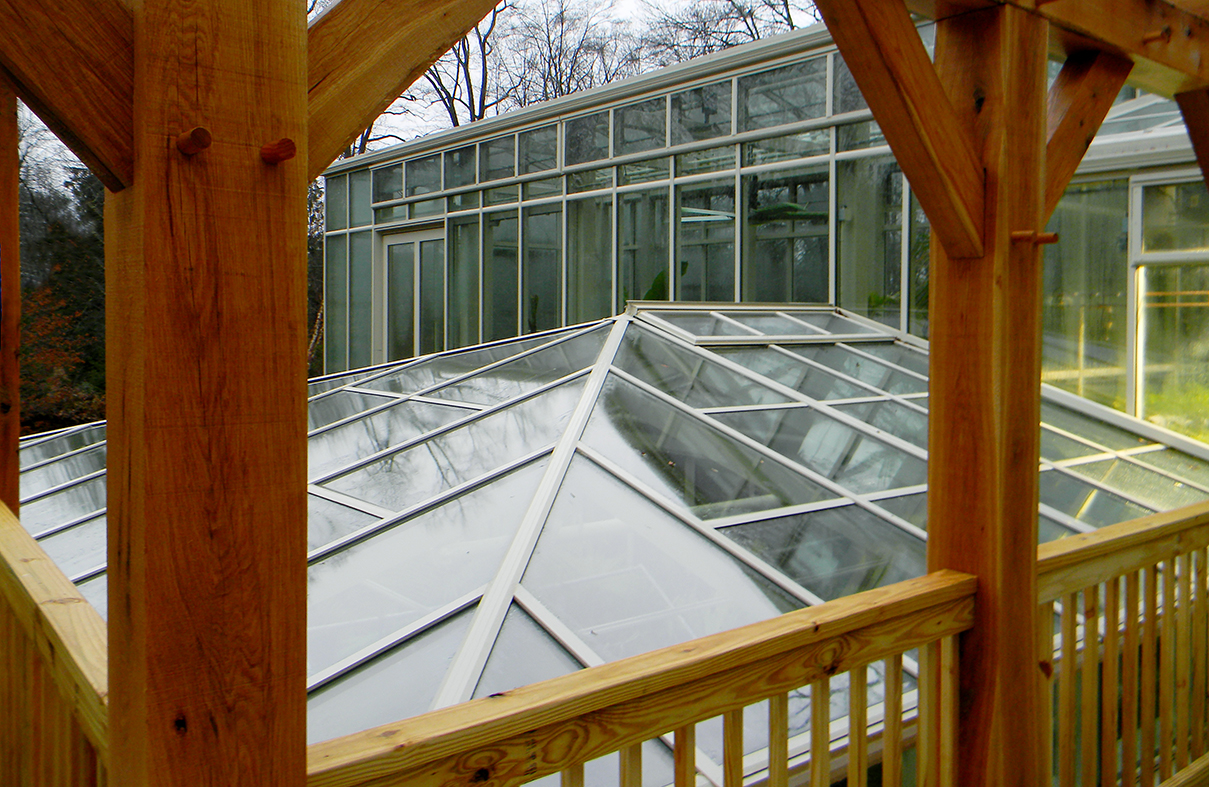 Straight eave double pitch greenhouse with 2 partial side walls, interior partition wall, and straight eave double pitch structure with hip end, connected to sidewall of main greenhouse. Cold frames are located on the exterior of the greenhouse. Interior growing accessories include ridge vents, eave vents, circulation fans, grow lights, and misting system.