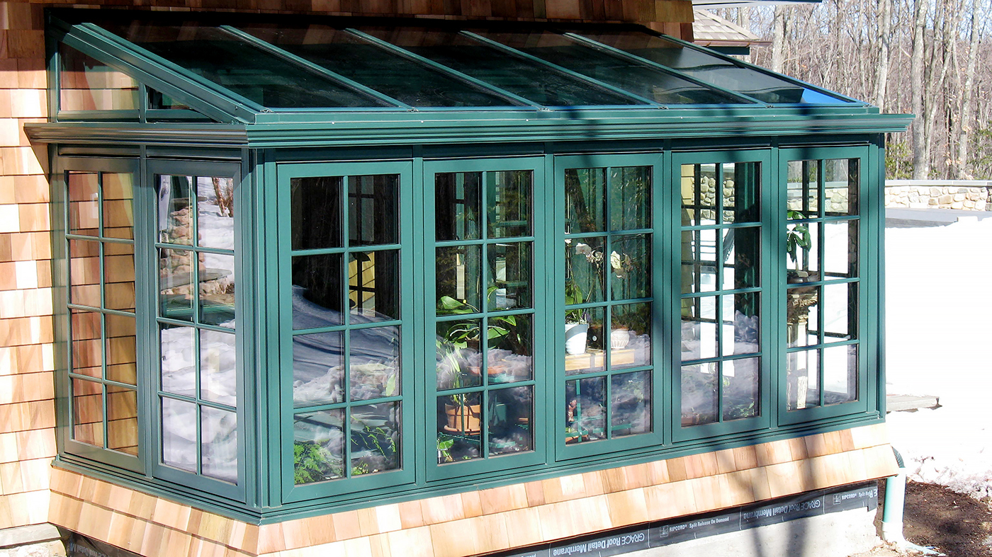 Straight eave lean-to sunroom with two gable ends, casement windows, and decorative elements including transom, gutter, and downspout.
