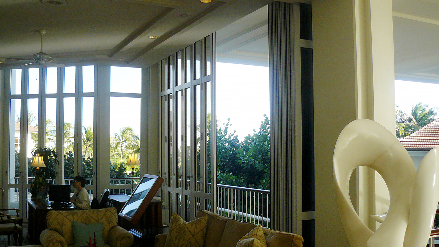 Multiple folding glass wall units used on a hotel including a center pivot folding wall with a split wall configuration and surface mount sill, sliding door and curtain wall, all with monolithic glazing.