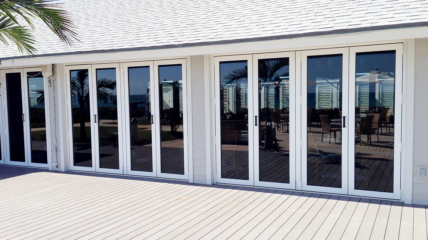 Multiple sets of folding glass walls, using recessed sills with adjustable ramps, located on a private beach club.