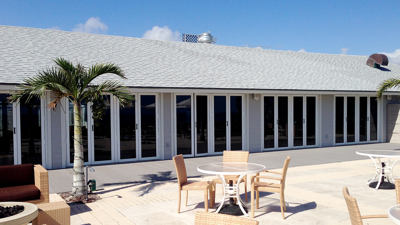 Multiple sets of folding glass walls, using recessed sills with adjustable ramps, located on a private beach club.