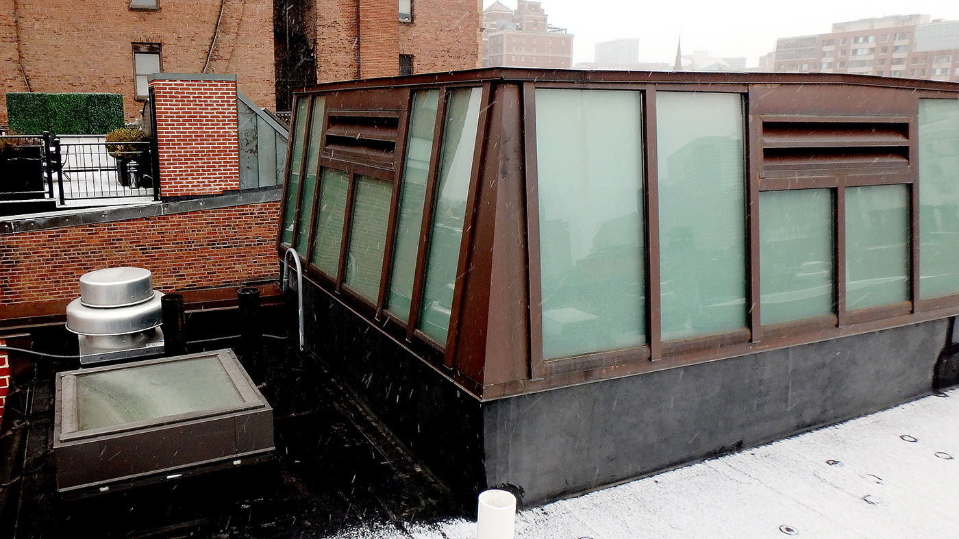 Lean-to skylight enclosing elevator shaft featuring Copper cladding exterior and white laminated glazing.