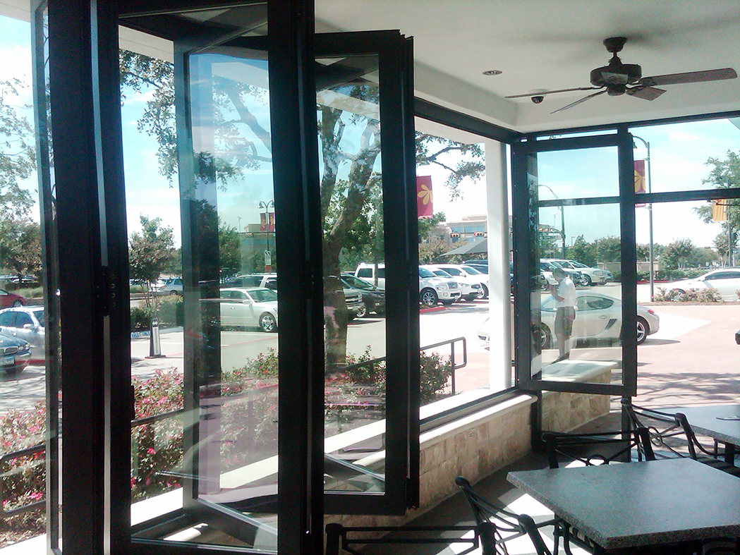 One segmented radius split folding glass wall with dual wheel trolley system - used in a restaurant setting.
