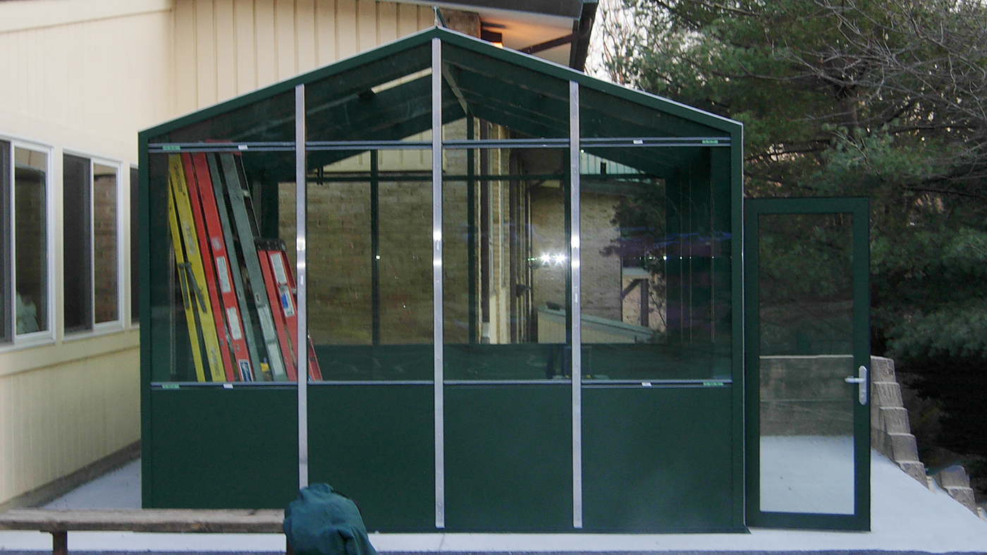 Straight eave double pitch greenhouse with two gable ends including circulating fans, eave vents, base panels and a terrace door.