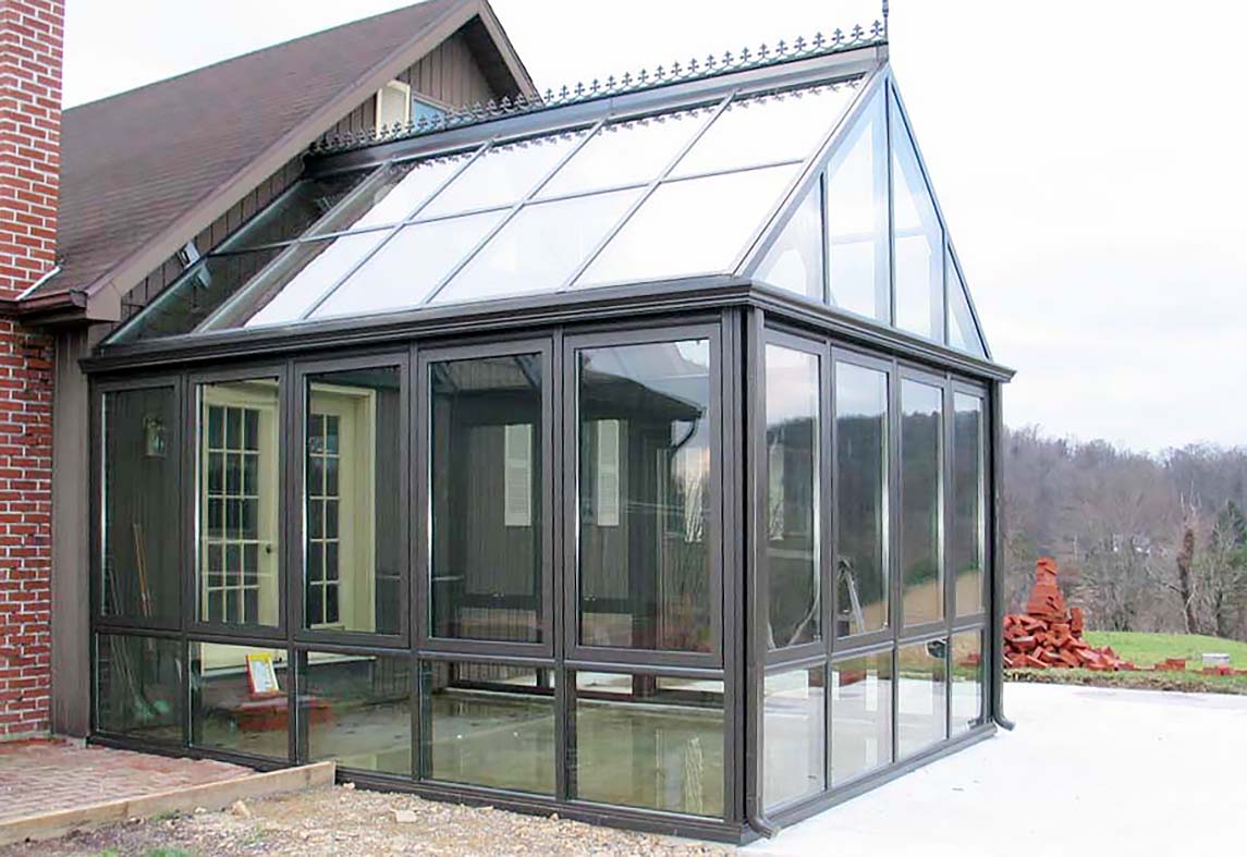 Straight eave, double pitch greenhouse with ridge vents, French doors, and decorative elements including ridge cresting and finial.