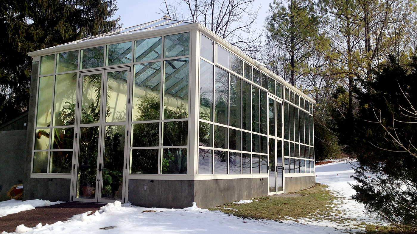 Two sets of massive French doors complement this tall standalone greenhouse.