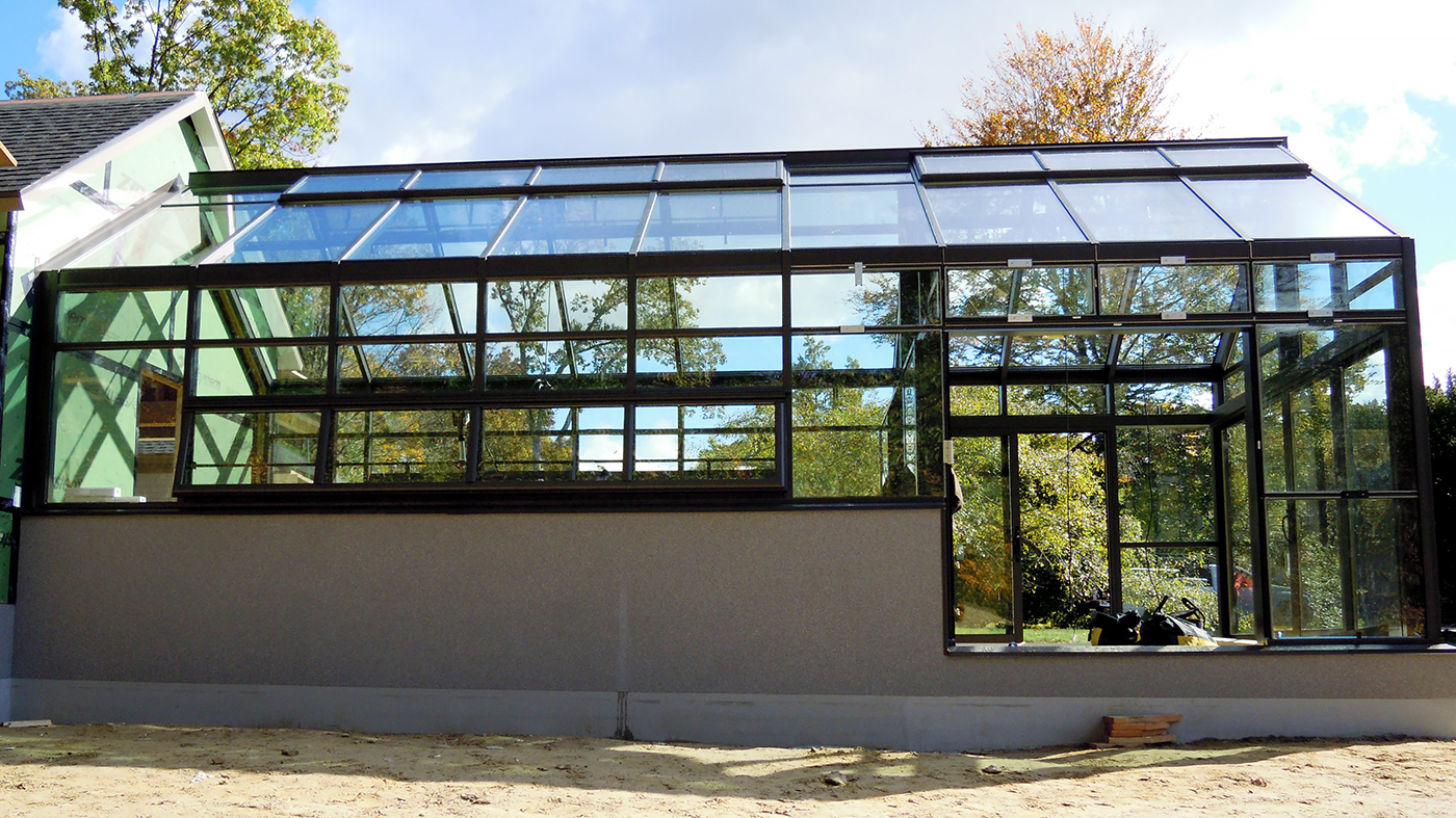 Straight eave lean-to greenhouse with one gable end and one interior wall. Unit features ridge vents, eave vents, sliding doors and an interior ring and collar.