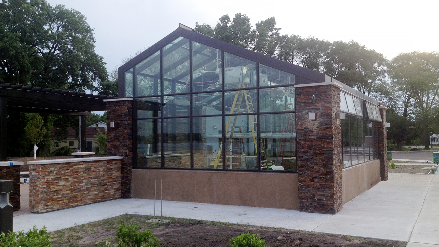 Irregular straight eave double pitch greenhouse with two gable ends, a cantilevered canopy, ridge vents, and eave vents used at a public park.