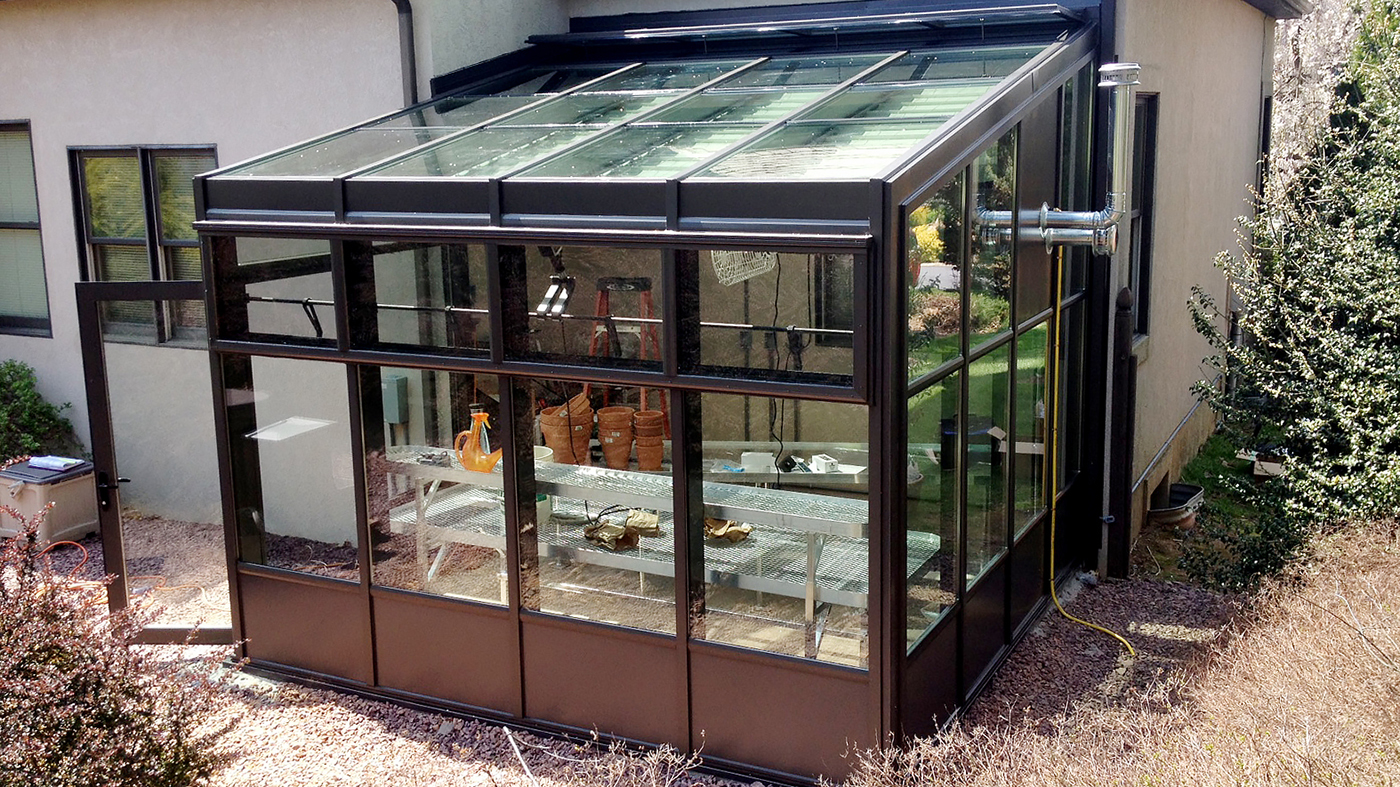 Straight eave lean-to greenhouse with interior roof mounted shades.