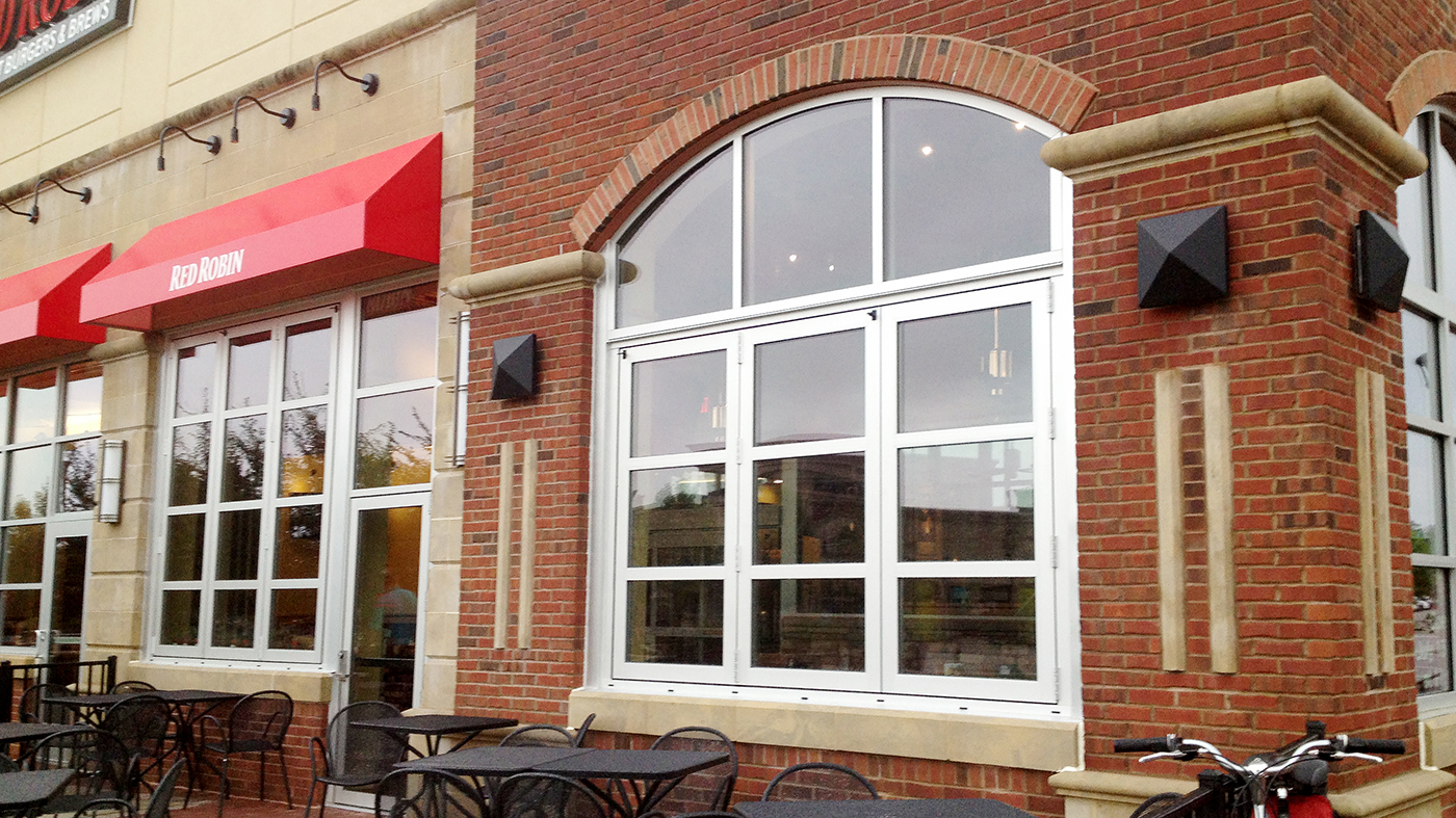 Folding glass wall, one folding window, vertical wall transom, and a terrace door used on a commercial restaurant application. The folding units feature all wall configuration, horizontal mullions, and standard sills.