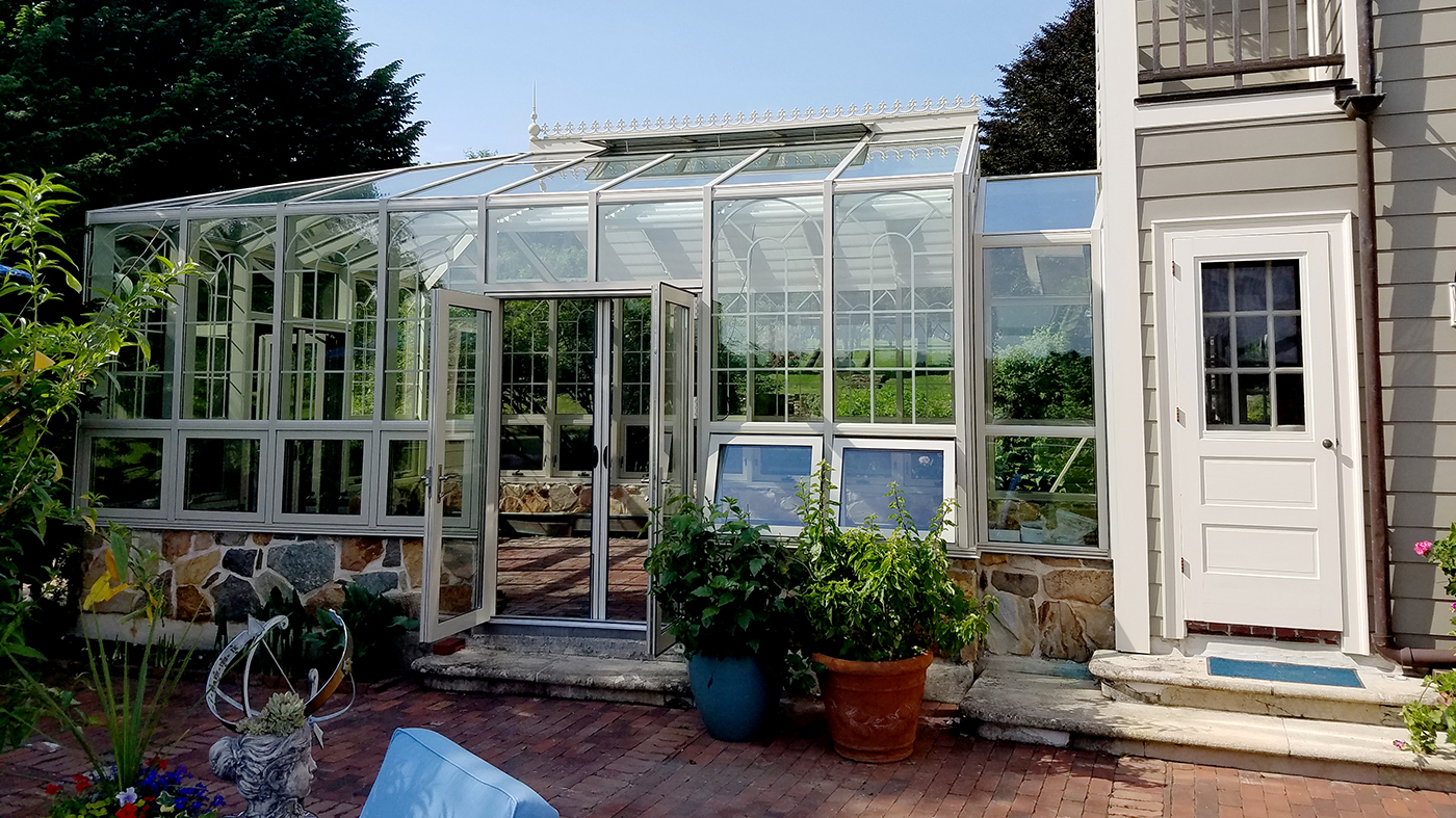 Straight eave double pitch hip end greenhouse with French doors and pleated screens.