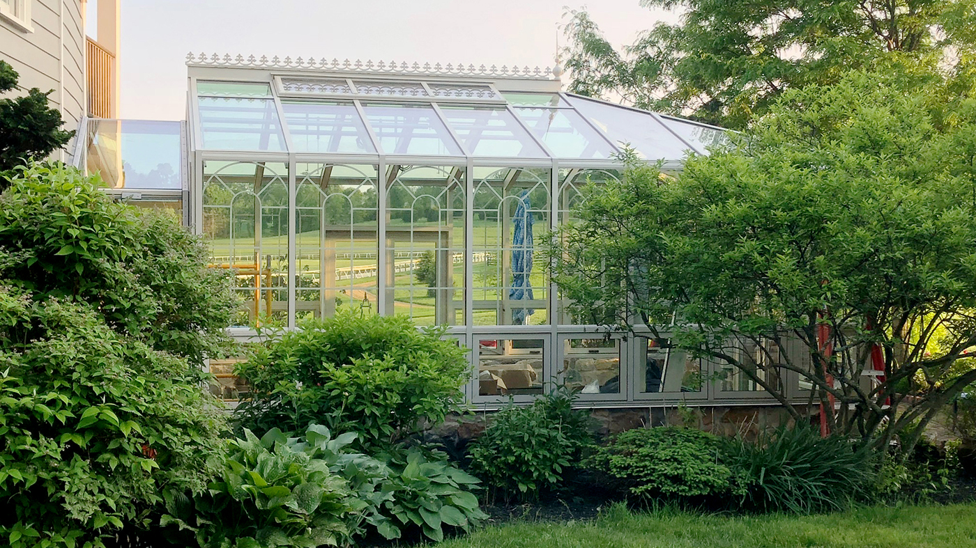 Straight eave double pitch hip end greenhouse with French doors and pleated screens.