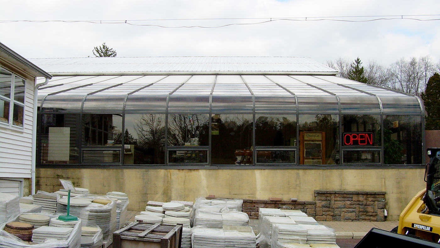 Curved eave lean-to greenhouse in this commercial end building supply store.