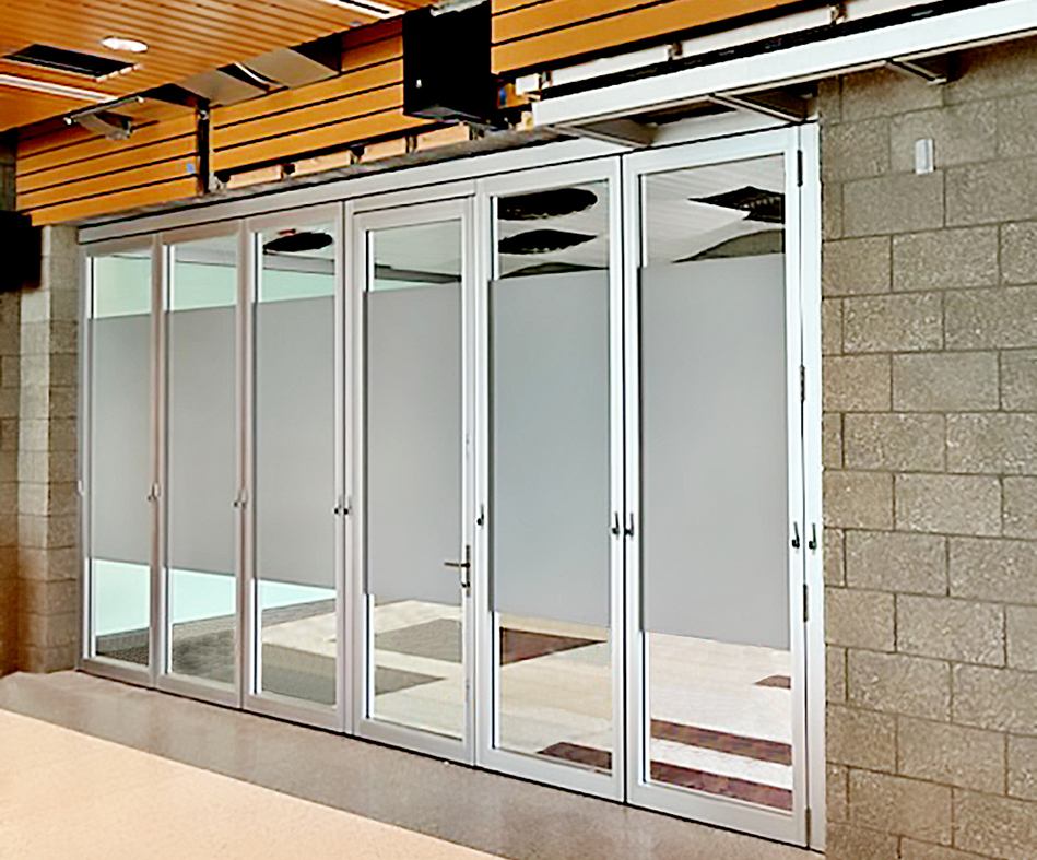 One six-panel G3LT slide and stack wall with a swing door integrated into the system and partially acid-etched glass panels.