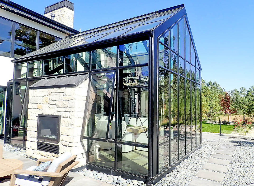 Straight eave double pitch conservatory with structural cross rods and glazed walkway to house with two sets of French doors.
