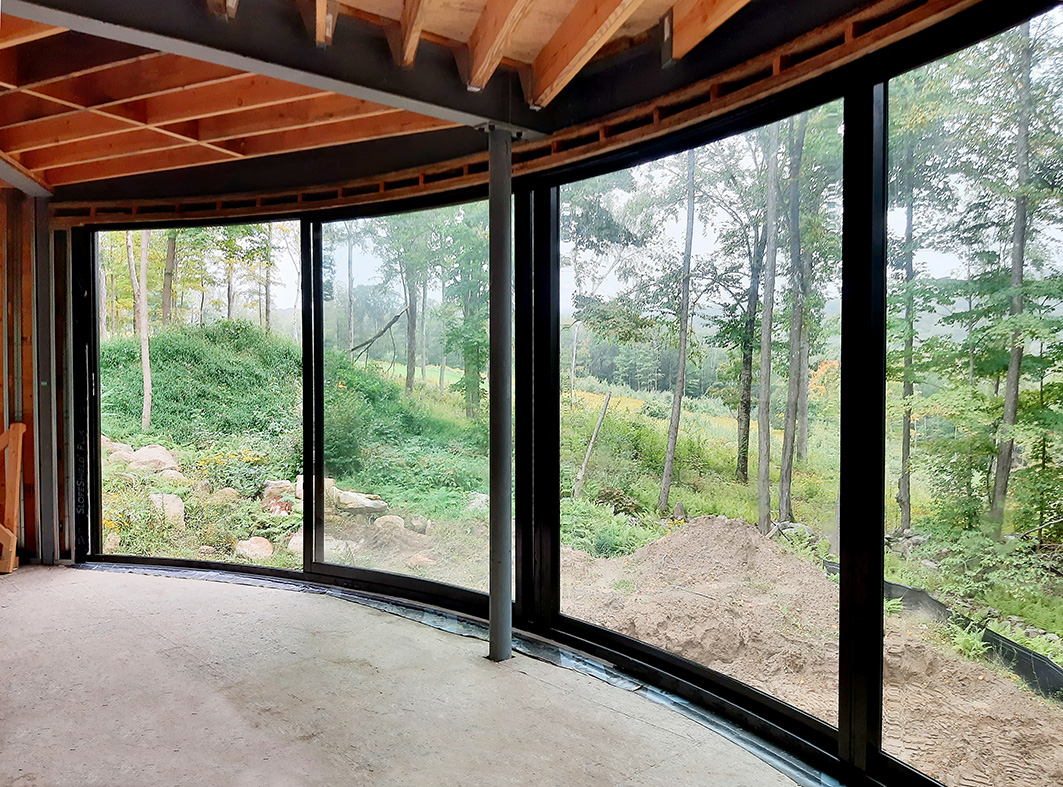 One true-radius, multi-track sliding glass door, one pivot door with two sidelites, one curtain wall with integrated sliding glass windows, one curtain wall with integrated sliding glass doors and two awning windows