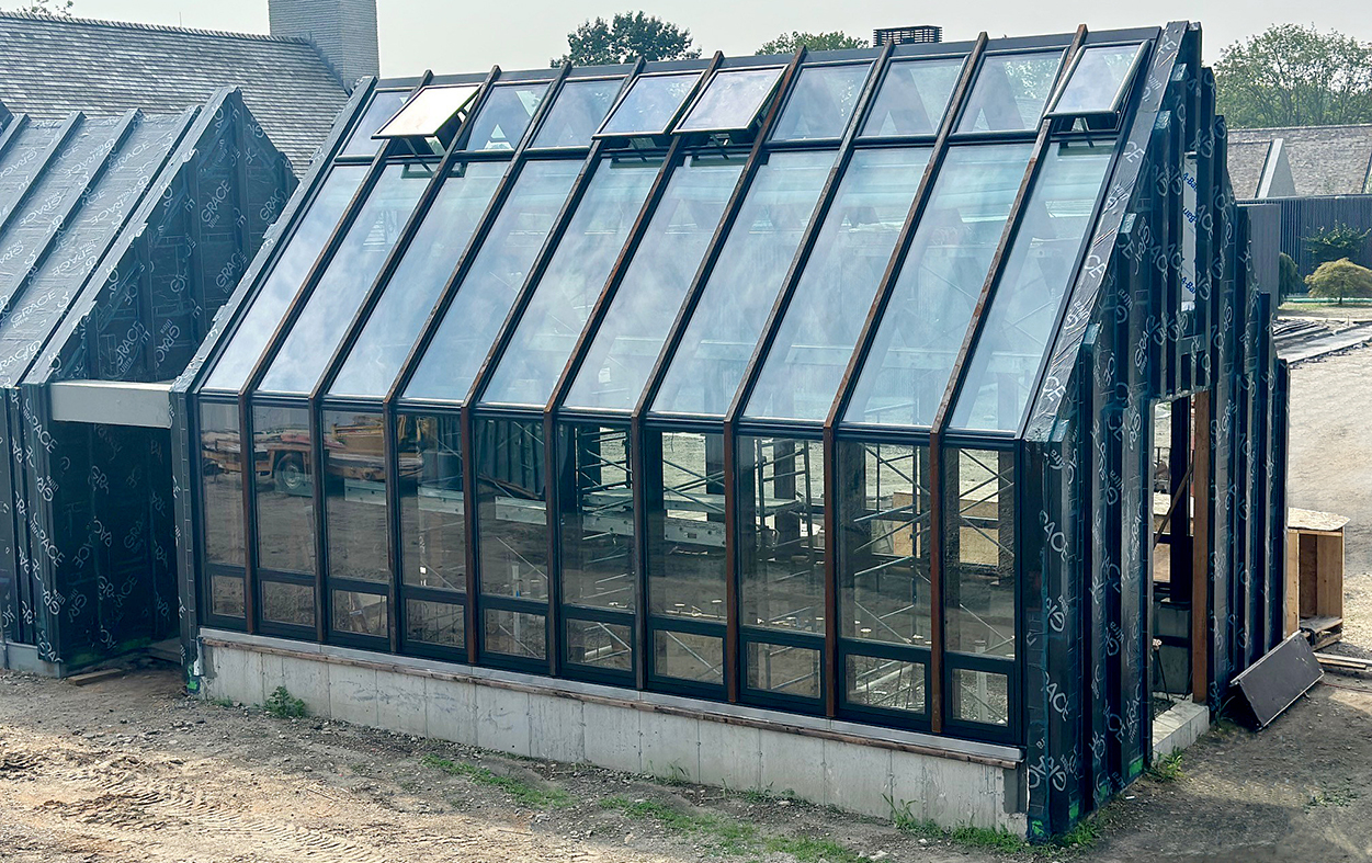 Straight eave double pitch greenhouse built with existing exposed steel framing. There are 20 awning windows and 20 motorized ridge vents using WindowMaster actuators.