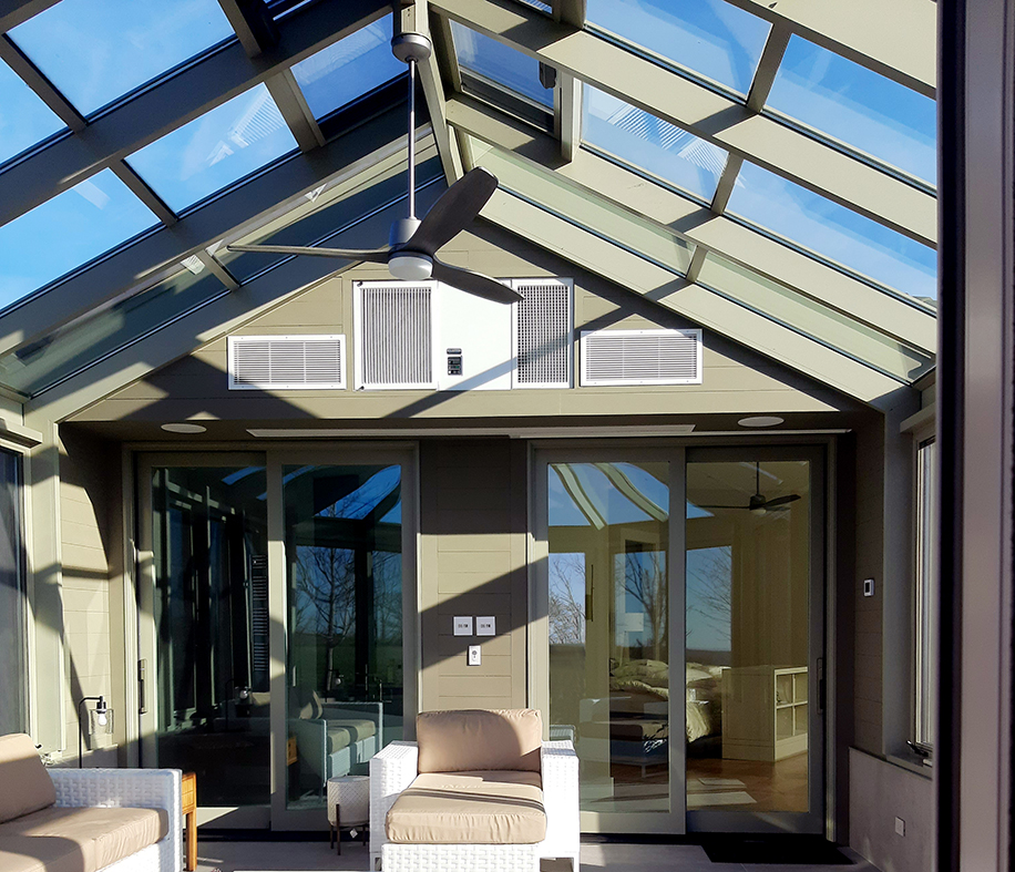 Straight eave double pitch bullnose end sunroom with two two-panel (OX configuration) integrated sliding glass doors and sliding screens. This unit includes a chain drive operator for the ridge vents and a faux hub and is topped with snow.