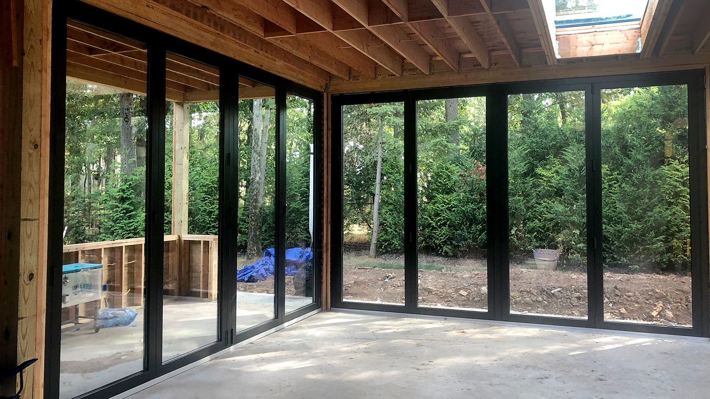 Eight fixed welded curb skylights, three four-panel outfold split wall bifold door units, and one aluminum curtain wall with an integrated swing door