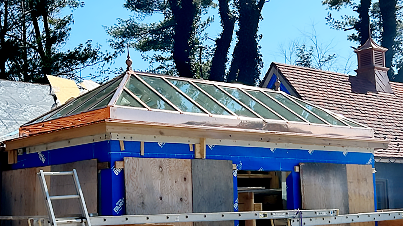 One straight eave double pitch skylight with two hip ends and a dormer that connects to building, clad in copper.