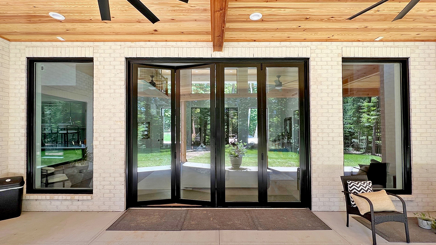 One G2 outswing French door with a solid panel infill and sidelites glazed with mirrored glass, one four-panel G2 infold split-wall bifold door units, and 10 G2 fixed windows.