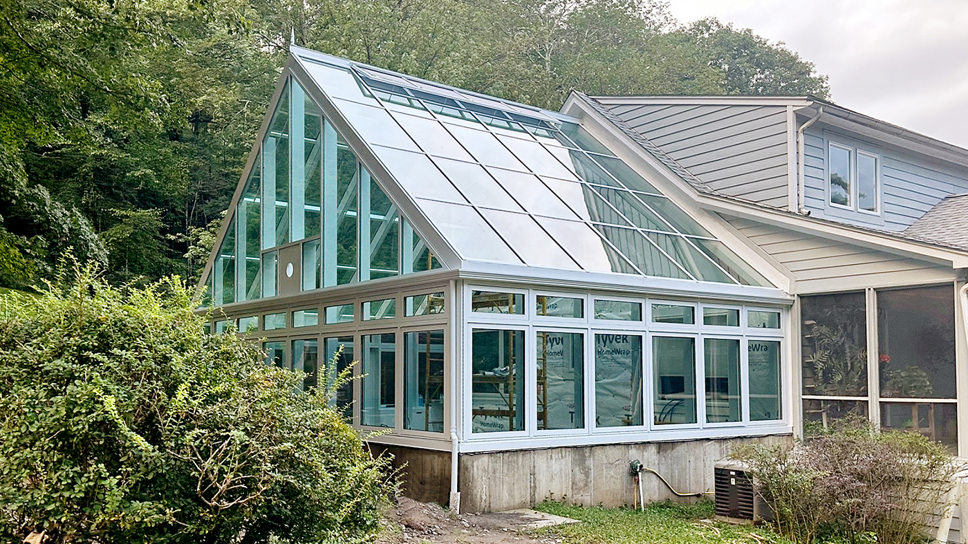 Straight eave double pitch conservatory with 10 motorized and eight manual awning windows and a solid panel to allow for heater exhaust.