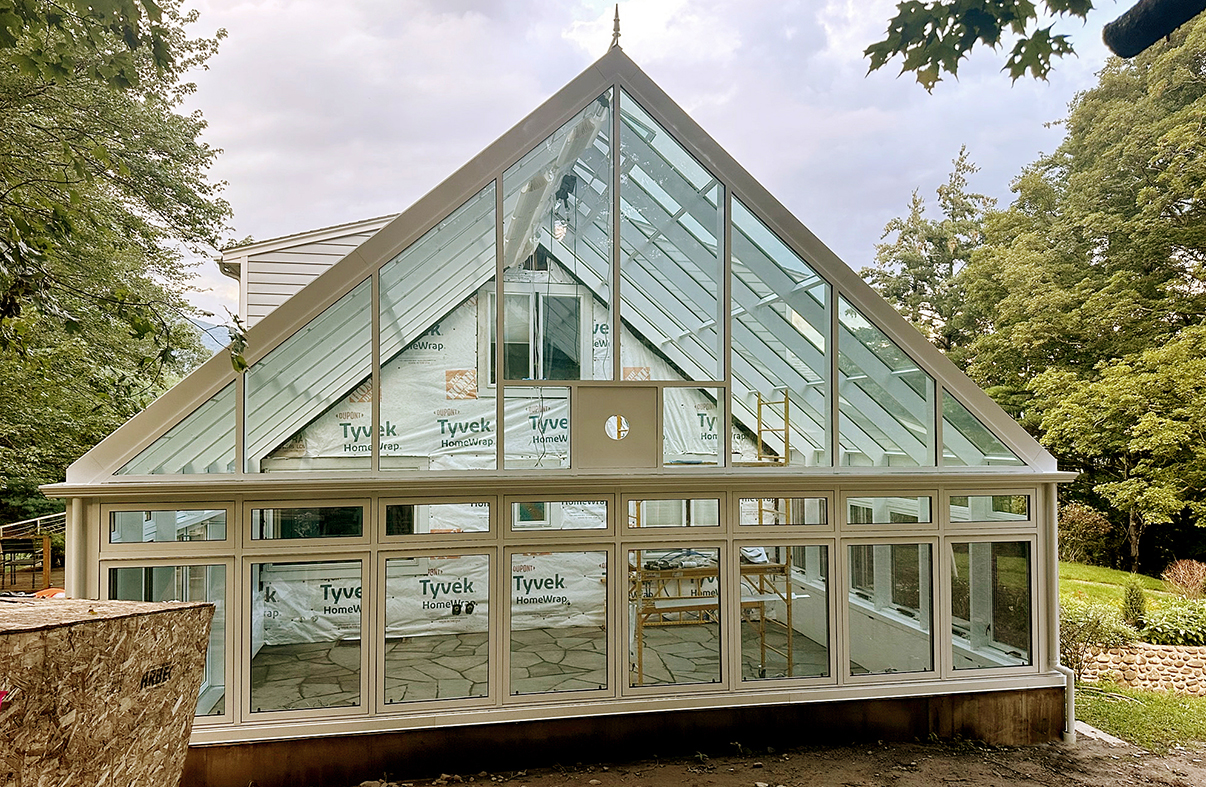 Straight eave double pitch conservatory with 10 motorized and eight manual awning windows and a solid panel to allow for heater exhaust.